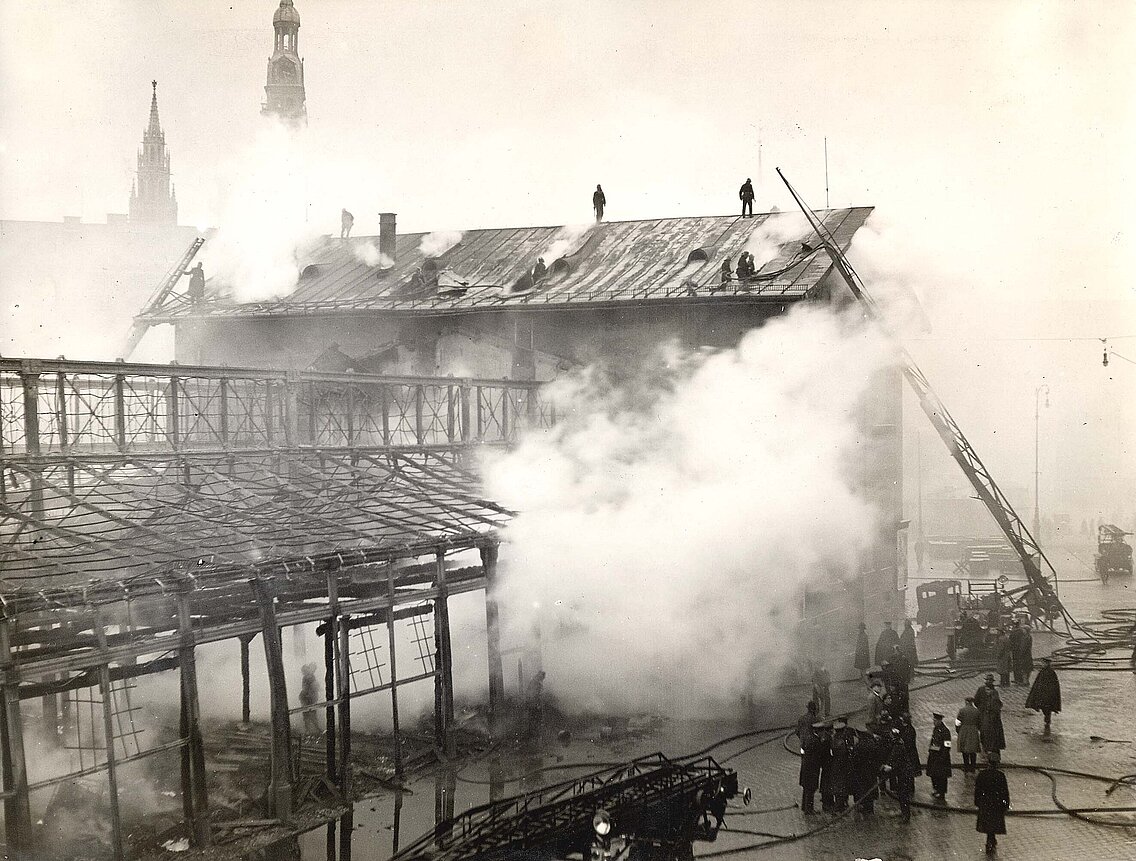 Feuerwehrmänner der Brandwache bei Nachlöscharbeiten der ausgebrannten Schrannenhalle und dem geöffneten Dach der Freibank